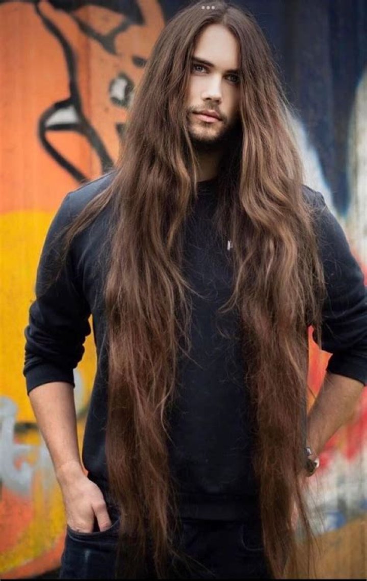 a man with long hair holding a knife in his right hand and looking at the camera